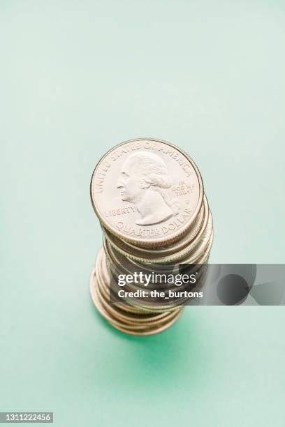 high angle view of a stack of us quarter coins on turquoise colored background - quarter foto e immagini stock
