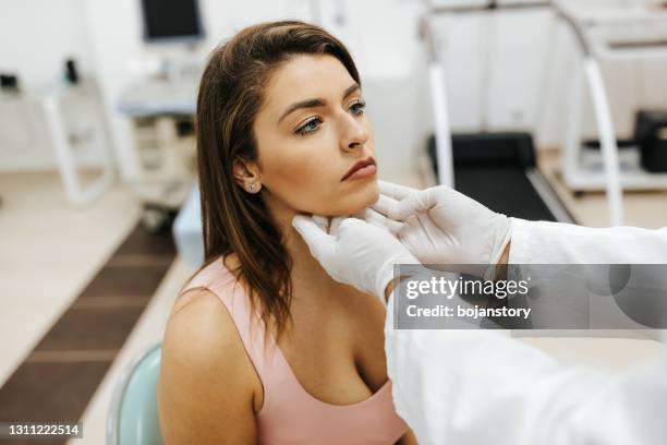 médico masculino examinó el dolor de cuello de una paciente femenina - thyroid gland fotografías e imágenes de stock