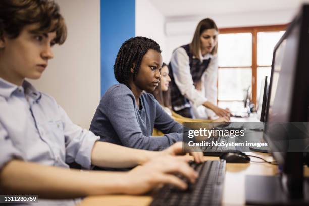 teacher assisting students using computer at the computer lab at high school - computer training stock pictures, royalty-free photos & images