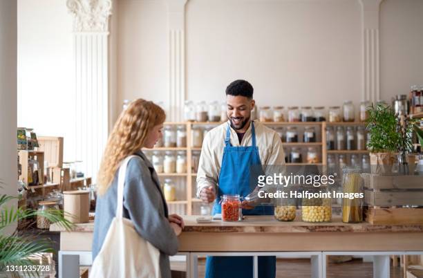 man shop assistant working in zero waste shop, serving customer. - retail assistant stock pictures, royalty-free photos & images