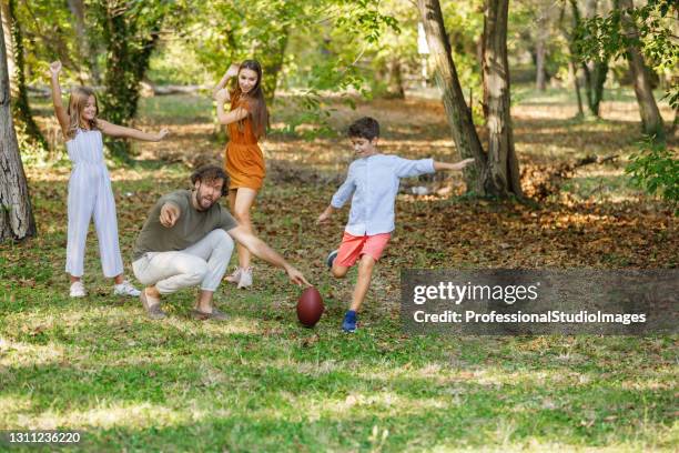 happy young family is playing with rugby ball outside in nature. - rugby kick stock pictures, royalty-free photos & images