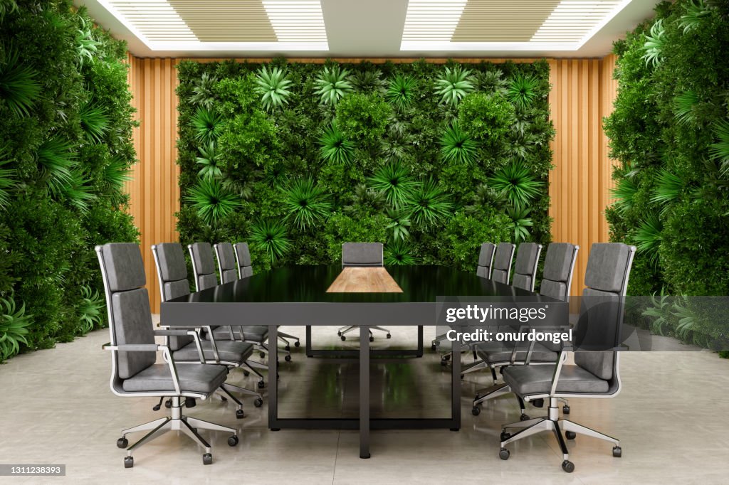 Moderner Tagungsraum-Innenraum mit Konferenztisch, Bürostühlen und Pflanzenwandhintergrund