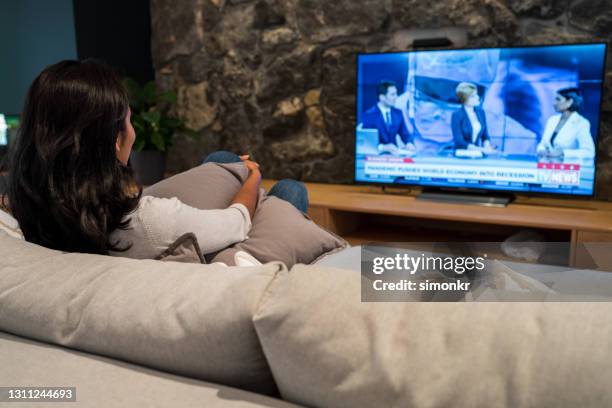 young woman watching news on television - back cushion stock pictures, royalty-free photos & images