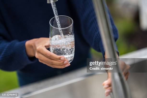 de handen die van de vrouw glas met water vullen - water garden stockfoto's en -beelden