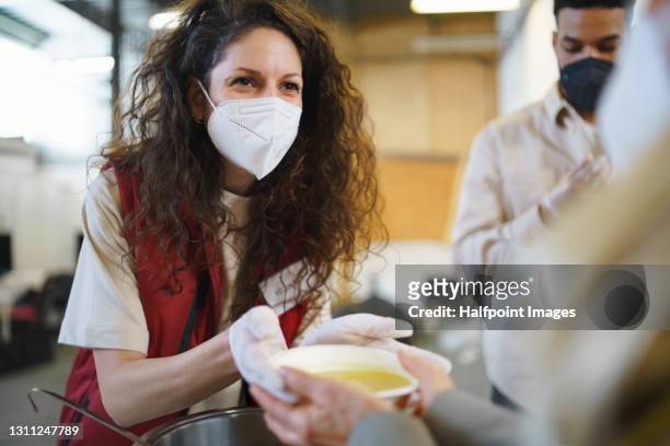 volunteers serving food in soup kitchen, poverty and coronavirus concept. - charity and relief work stock pictures, royalty-free photos & images