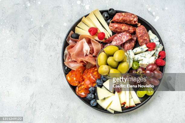 charcuterie board with italian salami, prosciutto, various cheeses and olives - mediterran menü stock-fotos und bilder