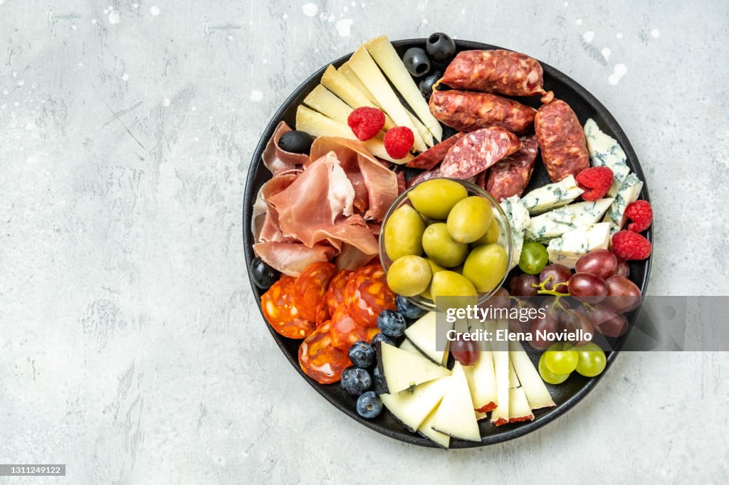 Charcuterie board with Italian salami, prosciutto, various cheeses and olives