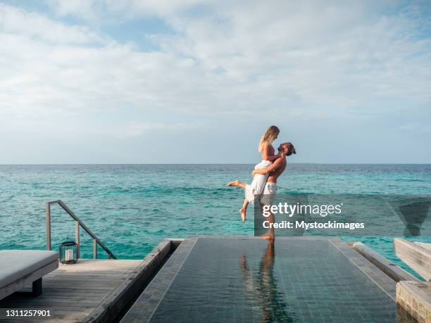 pareja abrazándose en el borde de la piscina infinita - maldivas fotografías e imágenes de stock