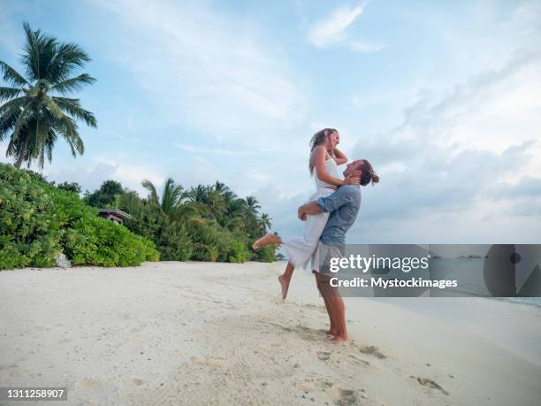 hombre levantando novia en playa tropical - luna de miel fotografías e imágenes de stock