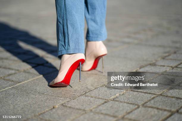 Natalia Verza @mascarada.paris wears a blue denim overall jumpsuit, pointed high heels shoes with red soles from Louboutin, on March 30, 2021 in...