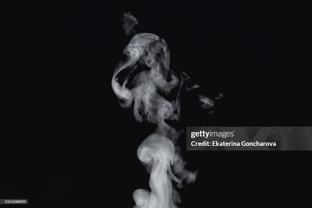 Beautiful white abstract steam from tea or coffee on a black isolated background.