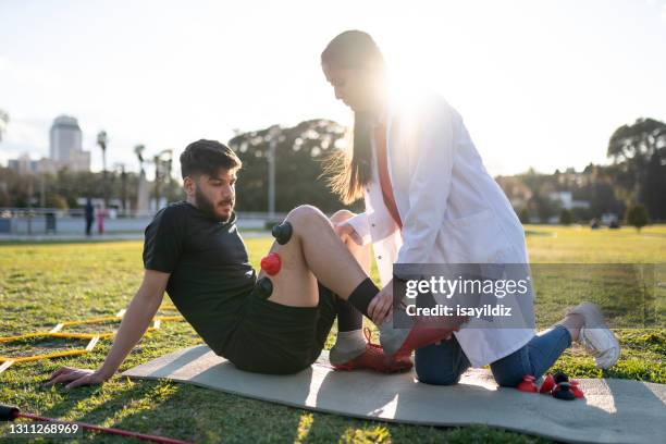 de jonge voetballer maakt fysiotherapiezitting met jonge vrouwelijke arts. - sports medicine stockfoto's en -beelden