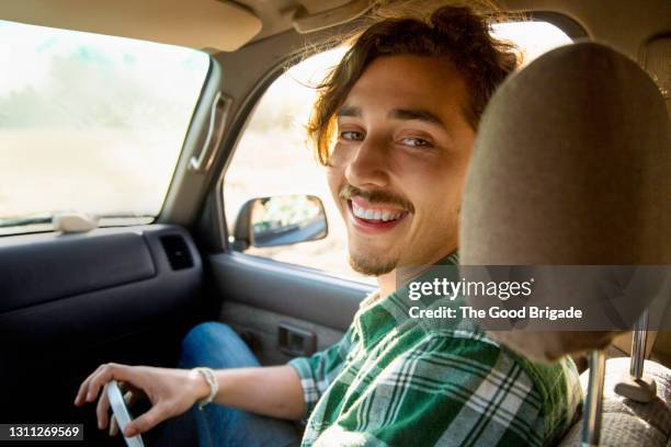 portrait of smiling young man sitting in car - punto di vista del guidatore foto e immagini stock