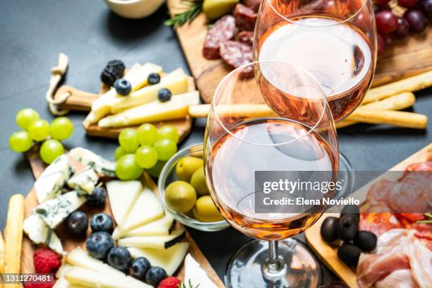 two glasses of rose wine with cheese and salami, olives - table aperitif stock-fotos und bilder