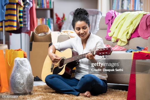 shot of a young women playing guitar, she is sitting on ground on carpet:- stock photo - woman playing guitar stock pictures, royalty-free photos & images