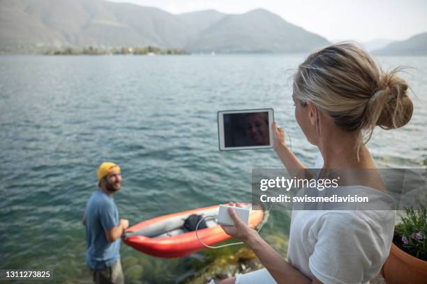 fin de semana junto al lago, hombre con canoa mujer con tableta - powerbank fotografías e imágenes de stock