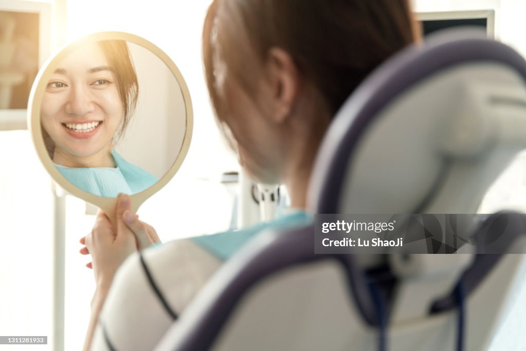 Young female woman checking her teeth after treatment