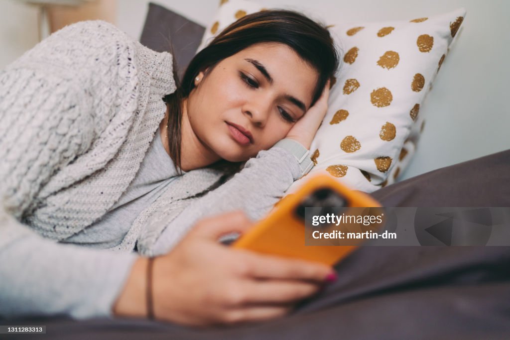 Woman in bed texting on phone
