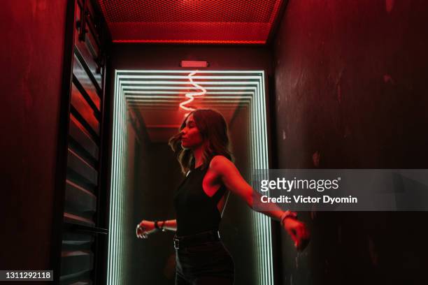 beautiful young brunette dances in the hall - dark background light stock-fotos und bilder
