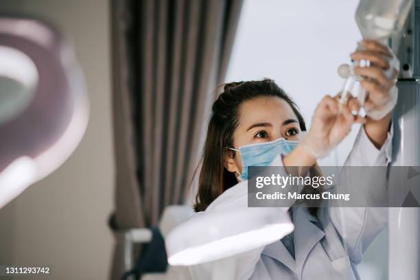 アジアの中国の女性看護師は、クリニックで生理液注射の準備と調整 - 生理食塩水 ストックフォトと画像