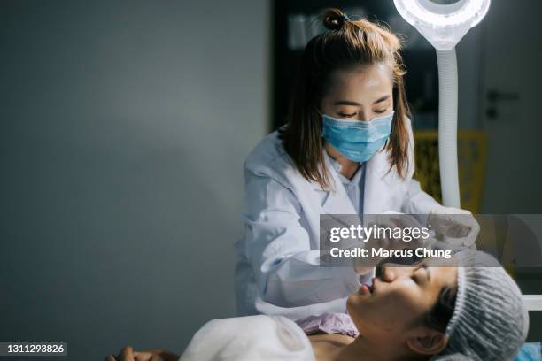 asian chinese women cosmetologist cleaning her customer face with cotton ball before the operation start in surgery room - woman applying cotton ball stock pictures, royalty-free photos & images