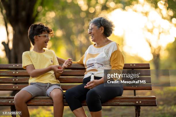grand-mère et petit-fils se reposant sur le banc dans la place - famille avec des lunettes de vue photos et images de collection