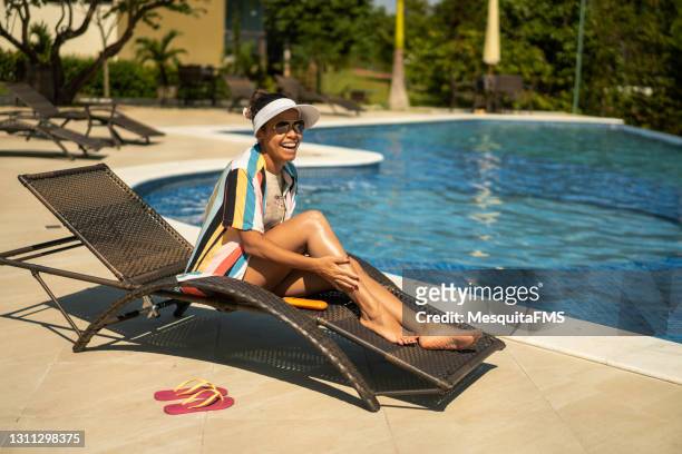 glimlachende toerist die naast het zwembad ontspant - latina legs stockfoto's en -beelden