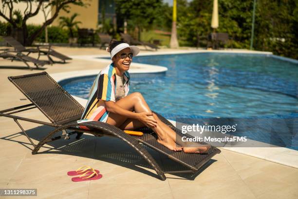 turista sorridente relaxando ao lado da piscina - women sunbathing pool - fotografias e filmes do acervo