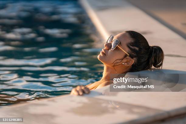 jonge vrouw die in de pool zonnebaadt - swimming pool stockfoto's en -beelden