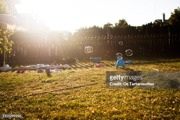 bubbles floating around and children items in a backyard at sunset - action plus general stockfoto's en -beelden