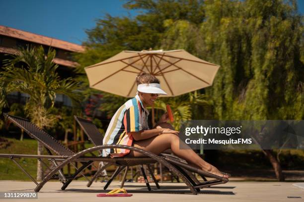 smiling woman sunbathing - patio umbrella stock pictures, royalty-free photos & images