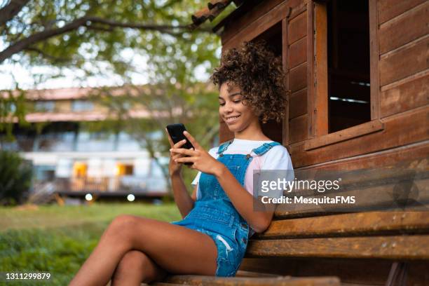teen girl using smartphone on the park bench - moving down to seated position stock pictures, royalty-free photos & images