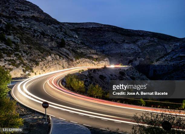 high angle view of moving car and truck lights circulating along a road of mountain with circular curves closed in the night. - arrows landscapes stock pictures, royalty-free photos & images