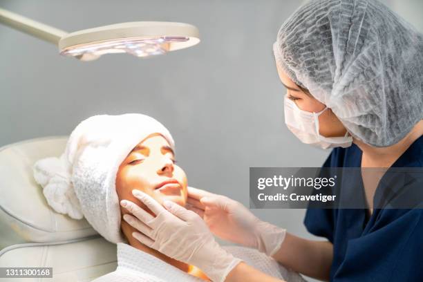 young woman doctor  with beauty woman in the beauty clinic backgrounds with receiving facial microdermabrasion treatment. - dermatology stock pictures, royalty-free photos & images