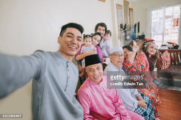 maleisische maleisische familie die selfiefoto neemt die camera bekijkt die thuis hari raya zwaait die hari raya viert - eid al fitr celebration to mark the end of ramadan stockfoto's en -beelden