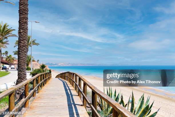 wooden boardwalk lead to the empty sandy beach of mil palmeras beach. alicante province. orihuela costa. spain - alicante stockfoto's en -beelden