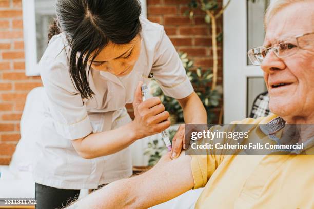 carer administers an insulin pen into elderly male's arm - insulin stock pictures, royalty-free photos & images