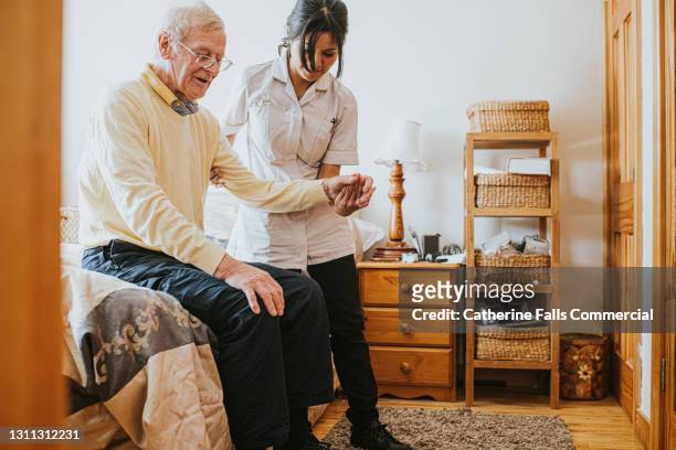 female carer assisting an elderly man in a bedroom - dignity elderly stock pictures, royalty-free photos & images