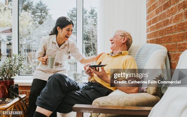 female care assistant spends some time with an elderly man in his home - asistencia de la comunidad fotografías e imágenes de stock