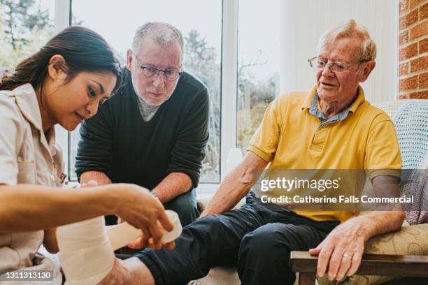 a healthcare worker bandages an elderly man's foot after an injury - ems fitness stock pictures, royalty-free photos & images