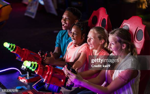 four children playing amusement arcade game - arcade stock pictures, royalty-free photos & images