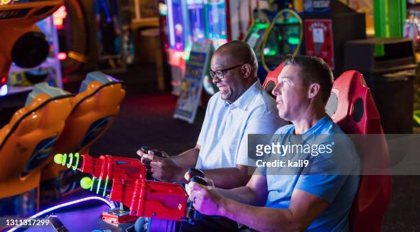 dos hombres jugando juego de arcade de diversión - sala de máquinas recreativas fotografías e imágenes de stock