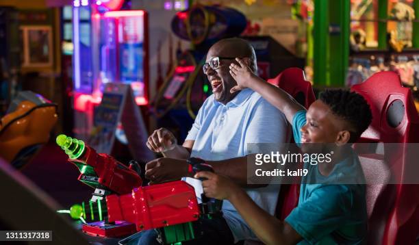 vater und sohn spielen spiel mit spielhalle - amusement arcade stock-fotos und bilder