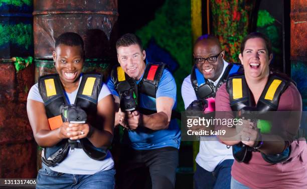 four multi-ethnic adults playing laser tag - laser game stock pictures, royalty-free photos & images