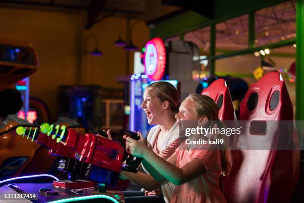 sisters playing amusement arcade game - amusement arcade stock pictures, royalty-free photos & images