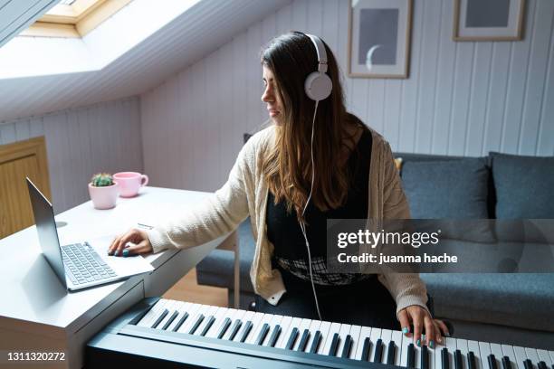 woman having online piano lessons with her laptop while staying at home. - keyboard player fotografías e imágenes de stock