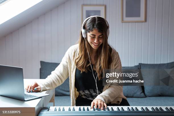 young woman having an online piano class on her laptop. - piano key stock pictures, royalty-free photos & images