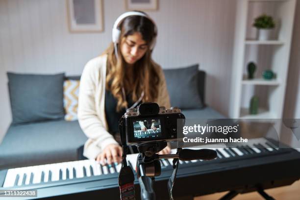 woman making a video with a camera while playing the piano at home. - musical stock-fotos und bilder