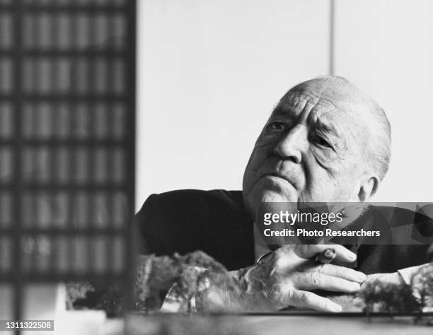 Portrait of German-American architect Ludwig Mies van der Rohe , a cigar in his hand, as he looks at a model of his design for the Toronto-Dominion...