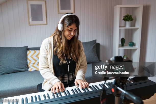 woman making a video with a camera while playing the piano at home. - musical instrument foto e immagini stock